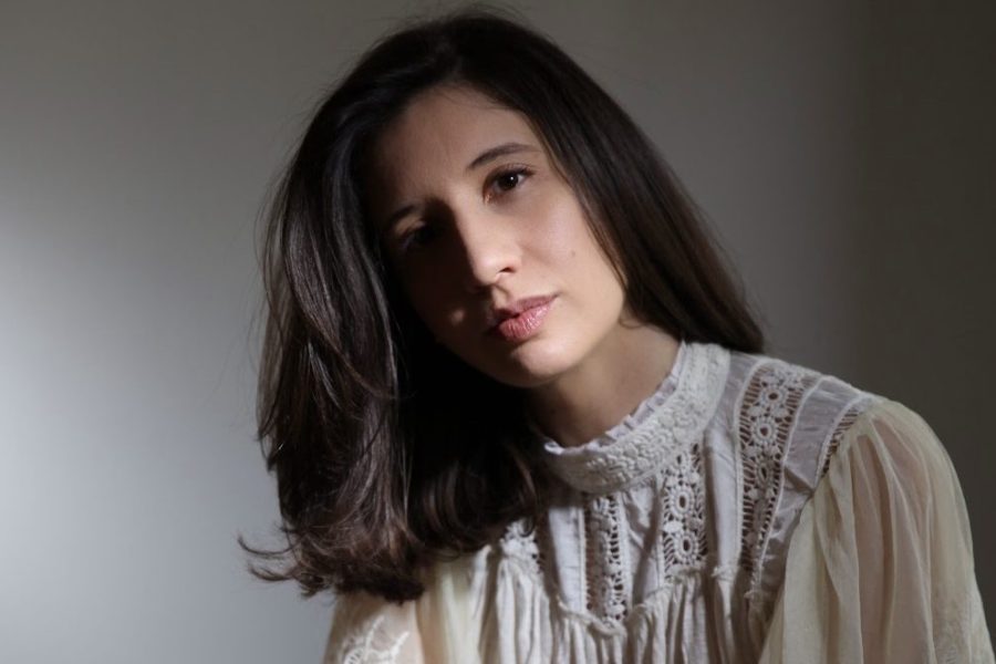 woman with long brown hair and white blouse looking towards the camera