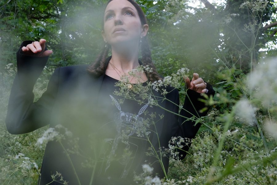 Woman in a black coat surrounded with foliage