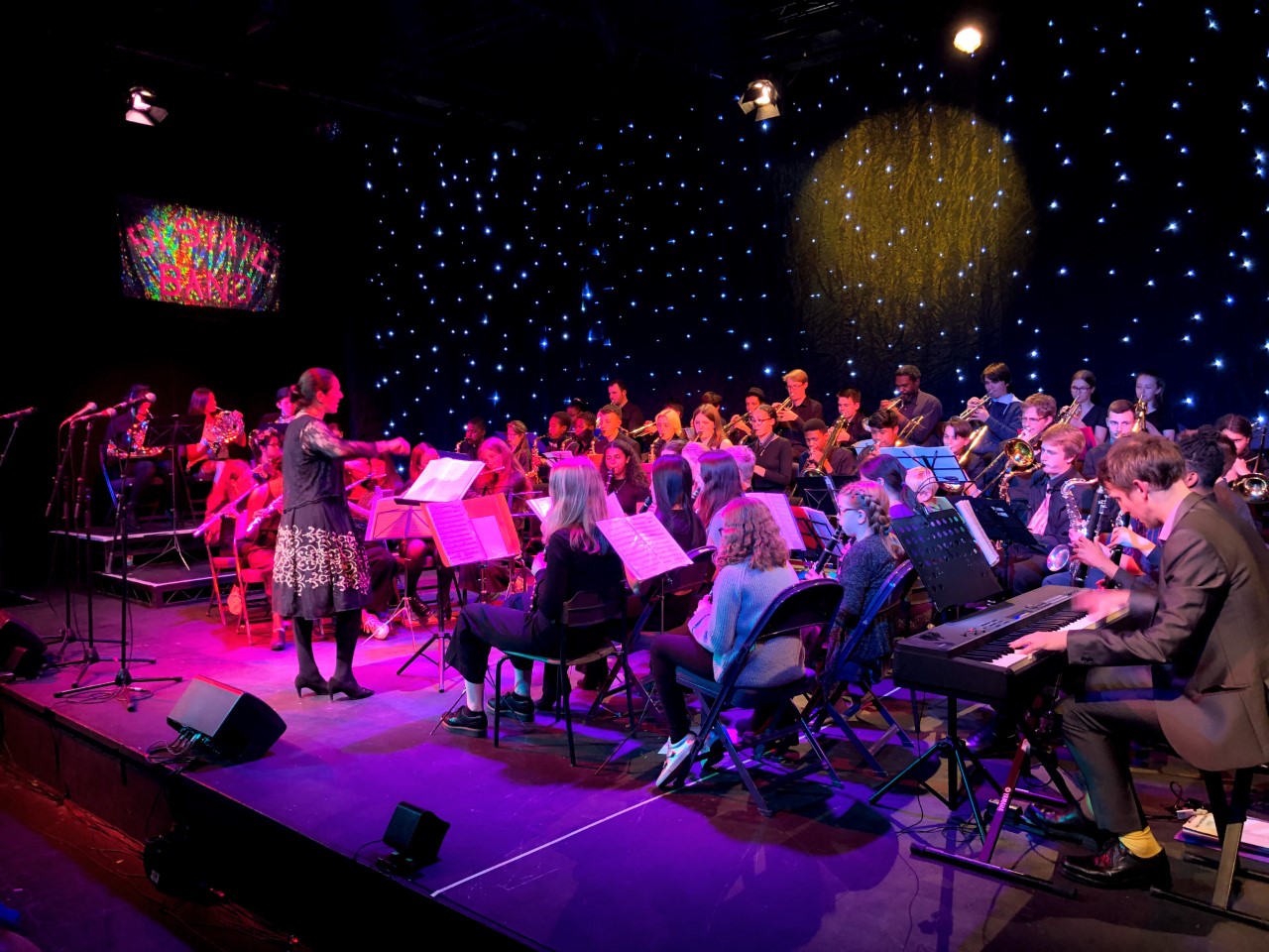 Band performing on stage with conductor