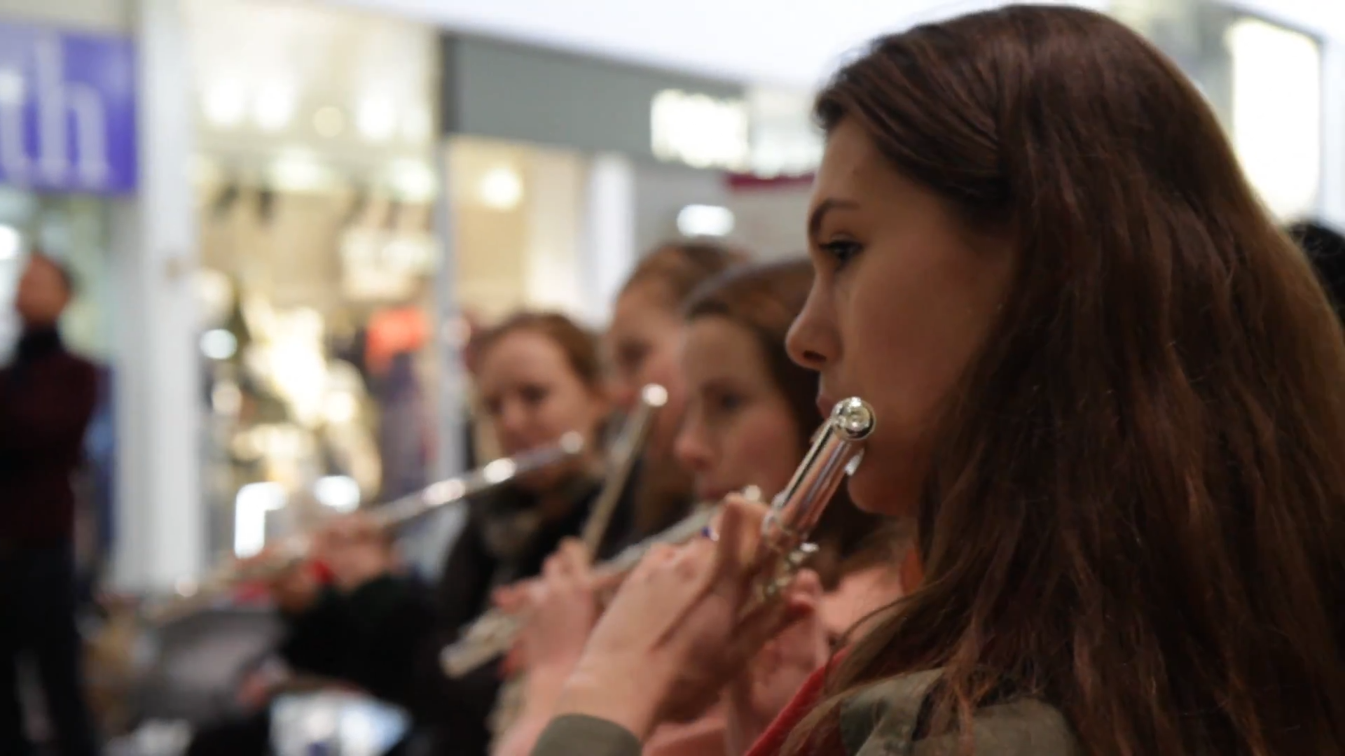 Girls playing flute with shops behind them
