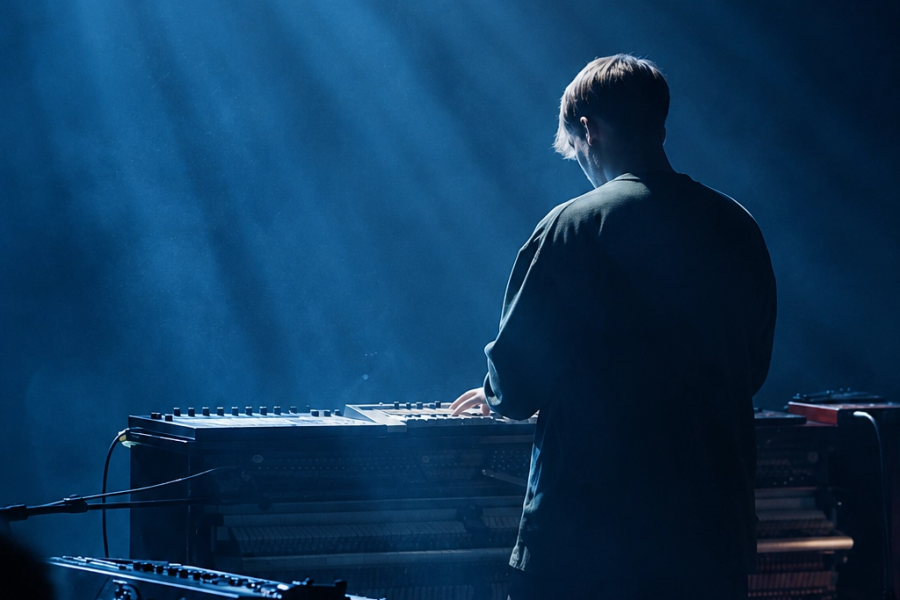 Musician standing in front of piano with light beaming down on him