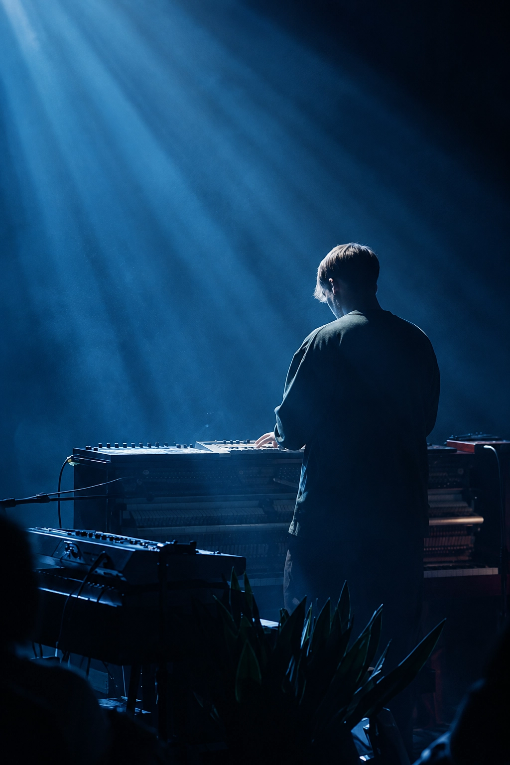 Musician standing in front of piano with light beaming down on him