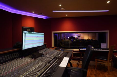 Recording studio and mixing desk shot, with window into performance space 