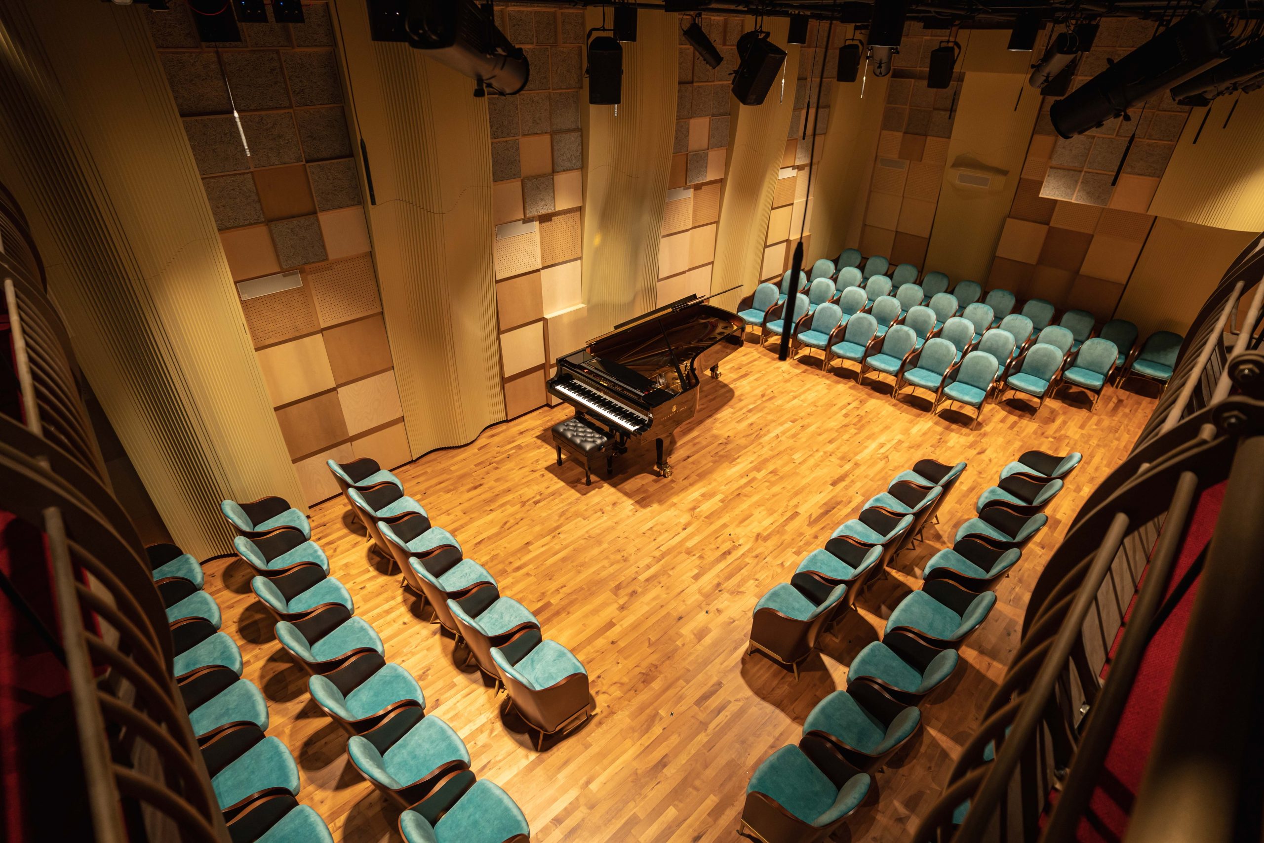 Concert hall seats laid out around a grand piano, shot taken from a balcony above