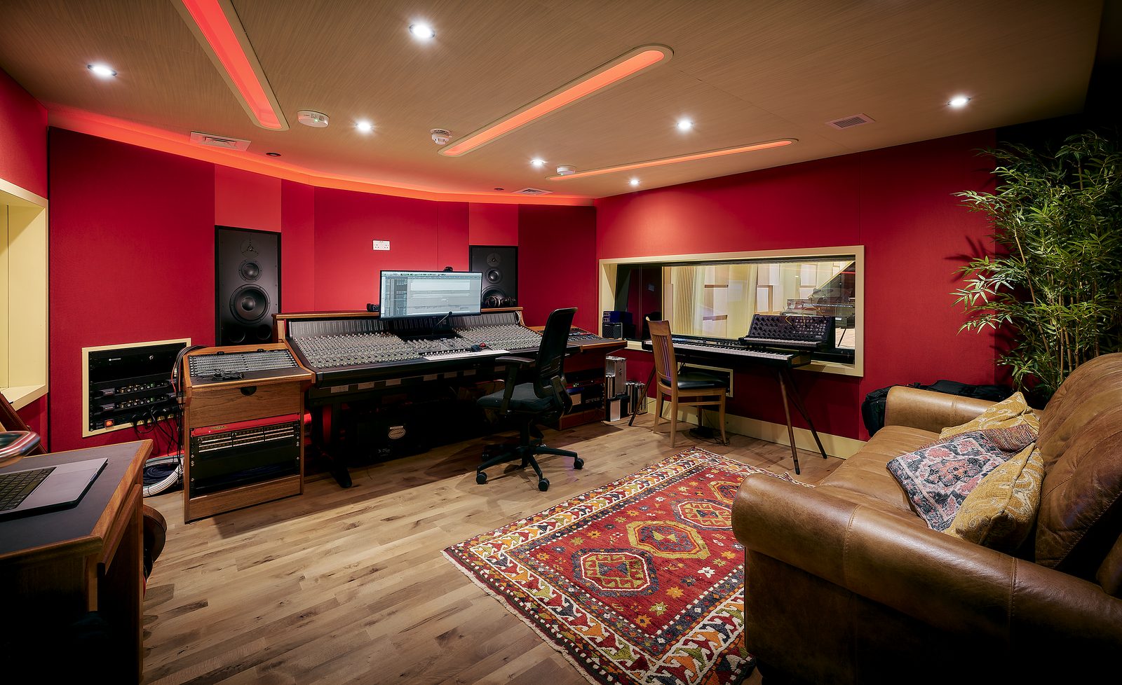 A recording studio, with sound desk and equipment, sofa and a rug