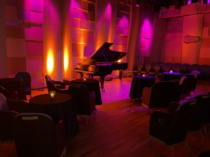 Embassy Gardens concert hall set with cabaret tables and red moodlighting