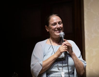 Sahana Gero smiling, and holding a microphone